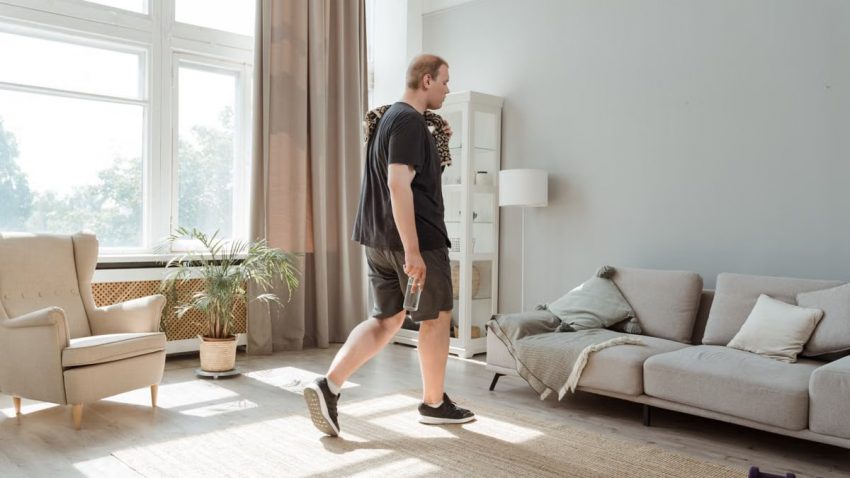 Plus size man in active wear working out in a sunny, modern living room.